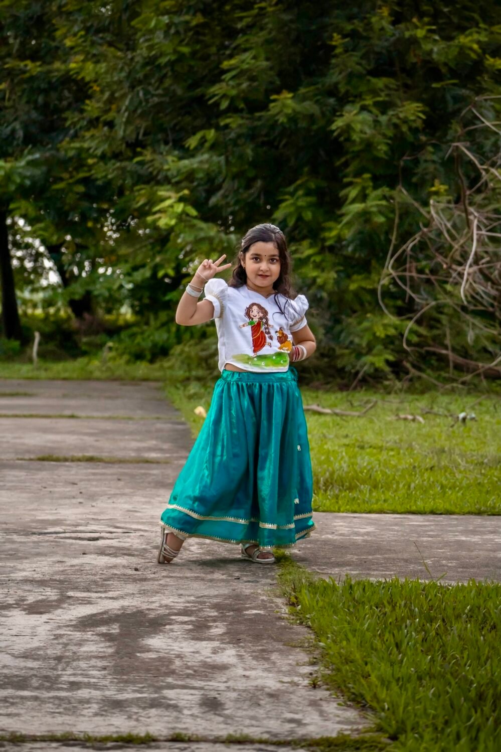 Young girl giving a peace sign in hand-painted Kanya Durga skirt set, perfect for festive celebrations.