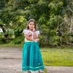 Full-length view of a girl posing in Aankibukis Couture Kanya Durga white and peacock green traditional skirt set.