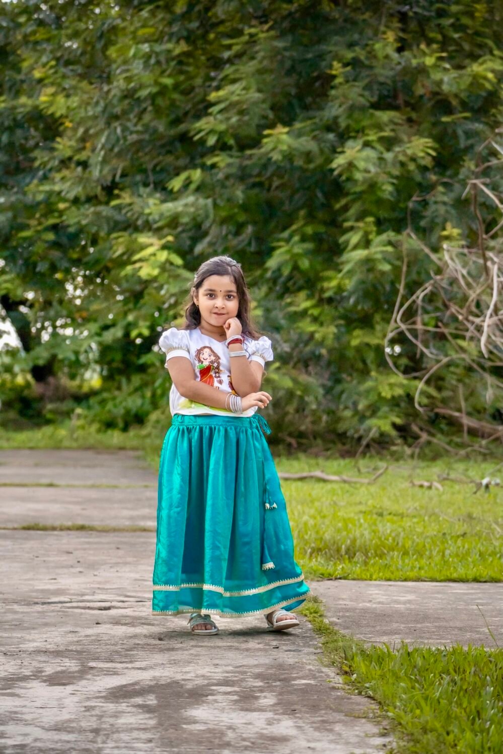 Full-length view of a girl posing in Aankibukis Couture Kanya Durga white and peacock green traditional skirt set.