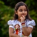 Detailed upper shot of a girl wearing a white malai cotton top featuring hand-painted Maa Durga art and gold lace trim.