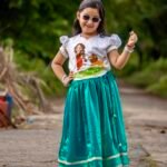 Little girl wearing sunglasses posing in Aankibukis Couture Kanya Durga skirt set with hand-painted Maa Durga top and peacock green skirt