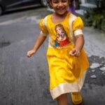 Smiling child running in the handpainted Durga Dulali yellow festive cotton frock by Aankibukis Couture.