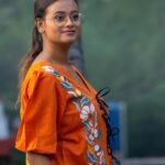 Side view of orange khadi shirt featuring handpainted floral painting and black doori tie closures.