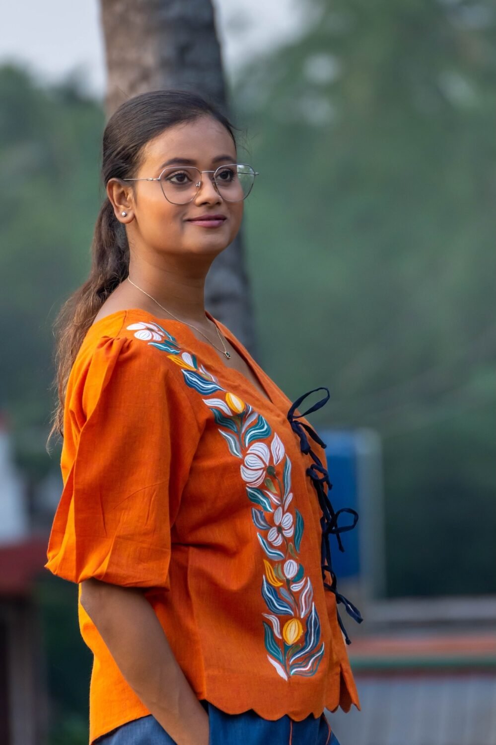 Side view of orange khadi shirt featuring handpainted floral painting and black doori tie closures.