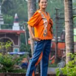 Woman wearing handpainted orange khadi top with scalloped hem and blue lava concept pants by Aankibukis Couture.