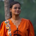 Close-up portrait of woman wearing orange handpainted doori top with floral motif and puff sleeves.