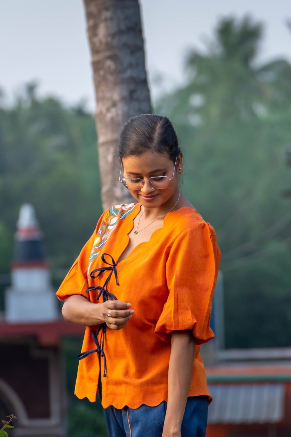 Close-up shot of handpainted orange shirt showing doori knots and scalloped bottom hemline.