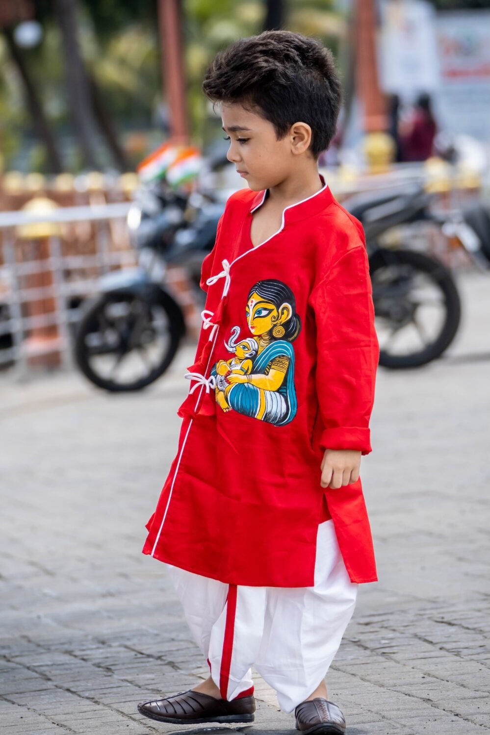 Side profile view of young boy wearing red and off white hand painted cotton dhoti kurta set for Durga Puja festival
