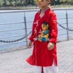 Boy walking outdoors wearing red hand painted Maa Ganna angrakha kurta with off white ready to wear dhoti set by Aankibukis Couture