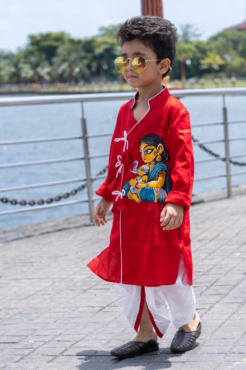Boy walking outdoors wearing red hand painted Maa Ganna angrakha kurta with off white ready to wear dhoti set by Aankibukis Couture