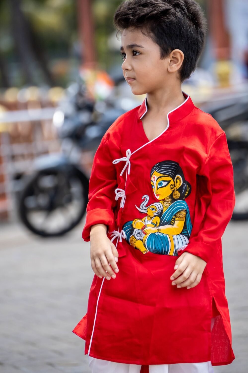 Close up shot of hand painted artwork showing Maa Durga holding baby Ganesha on red cotton angrakha kurta for boys