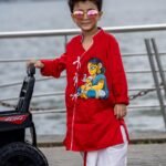 Boy posing next to a toy car wearing ready to wear hand painted cotton dhoti kurta set for kids festival wear