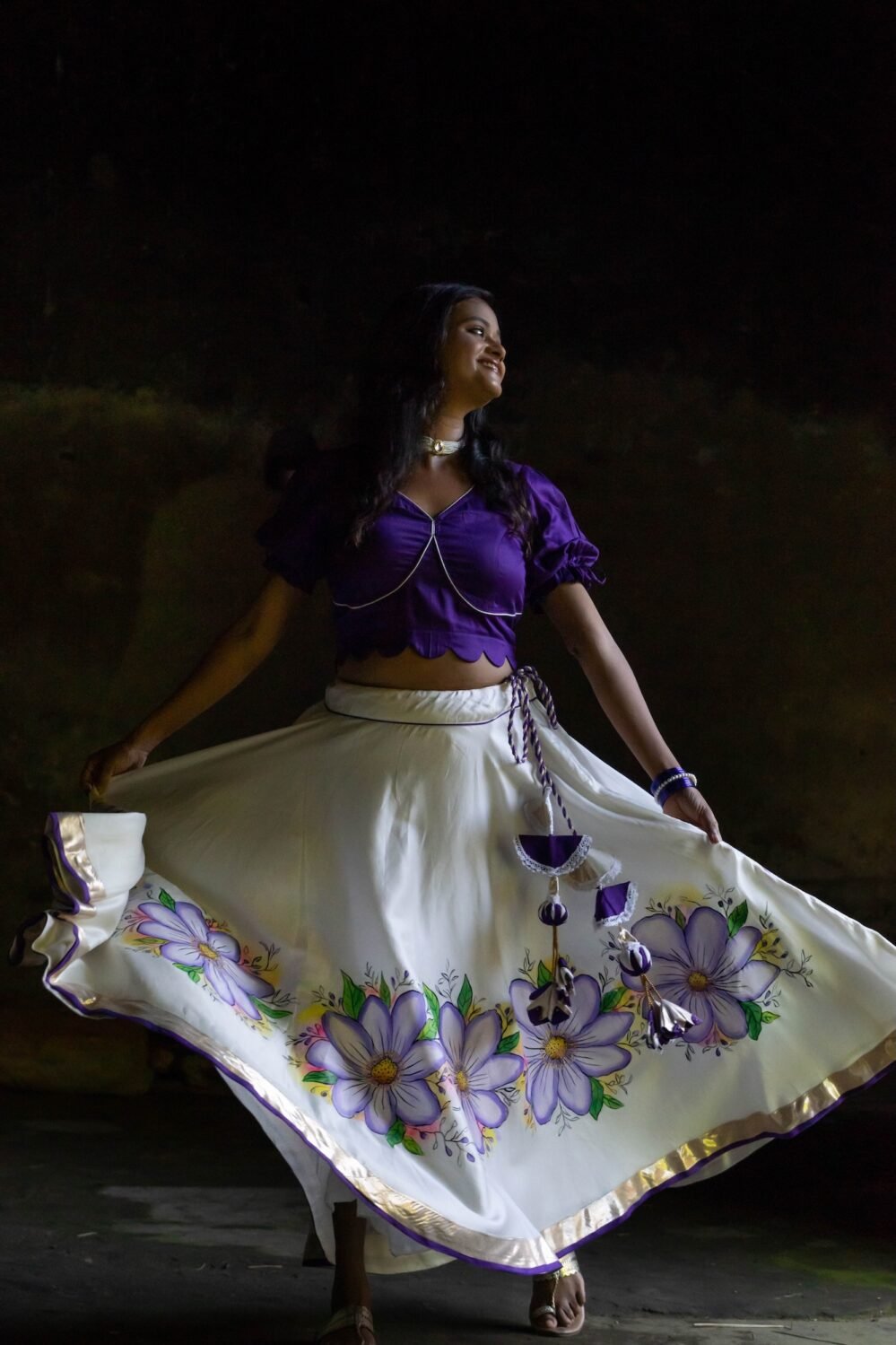 Model twirling in the Nilaambari off-white flared lehenga skirt showcasing the circular handpainted floral pattern and gold border.
