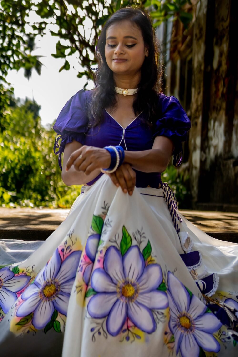 High-angle shot highlighting the intricate purple handpainted floral artwork and fabric texture of the Nilaambari lehenga skirt by Aankibukis Couture.