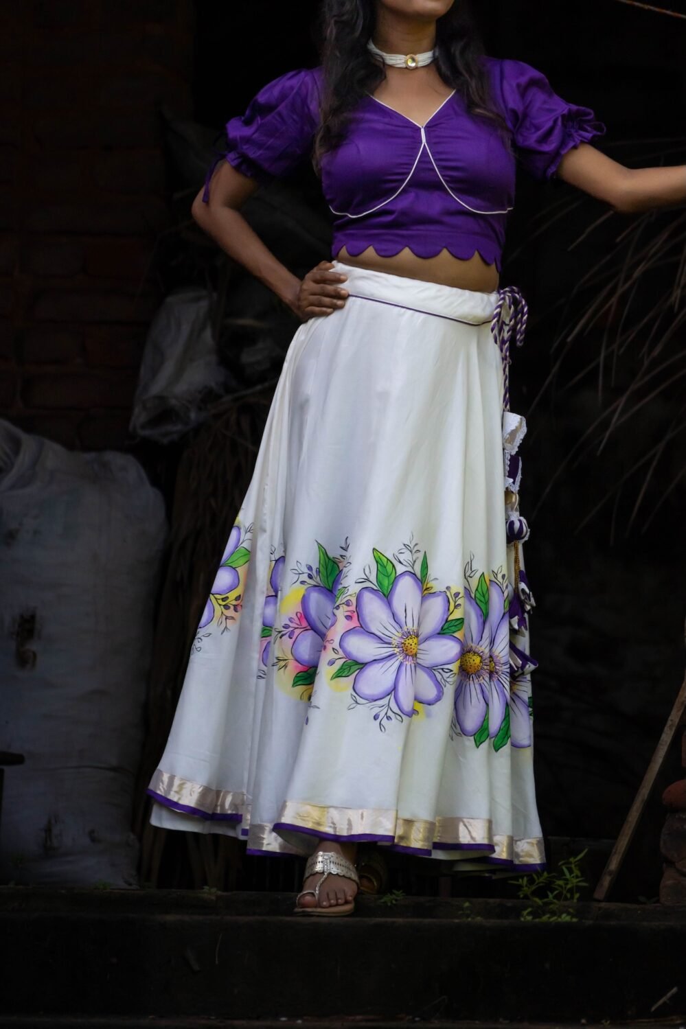 Medium shot highlighting the fit, hemline border, and handpainted violet botanical artwork on the Nilaambari lehenga set.