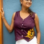 Model wearing a deep purple V-neck handpainted sunflower waist coat standing against a colorful backdrop.