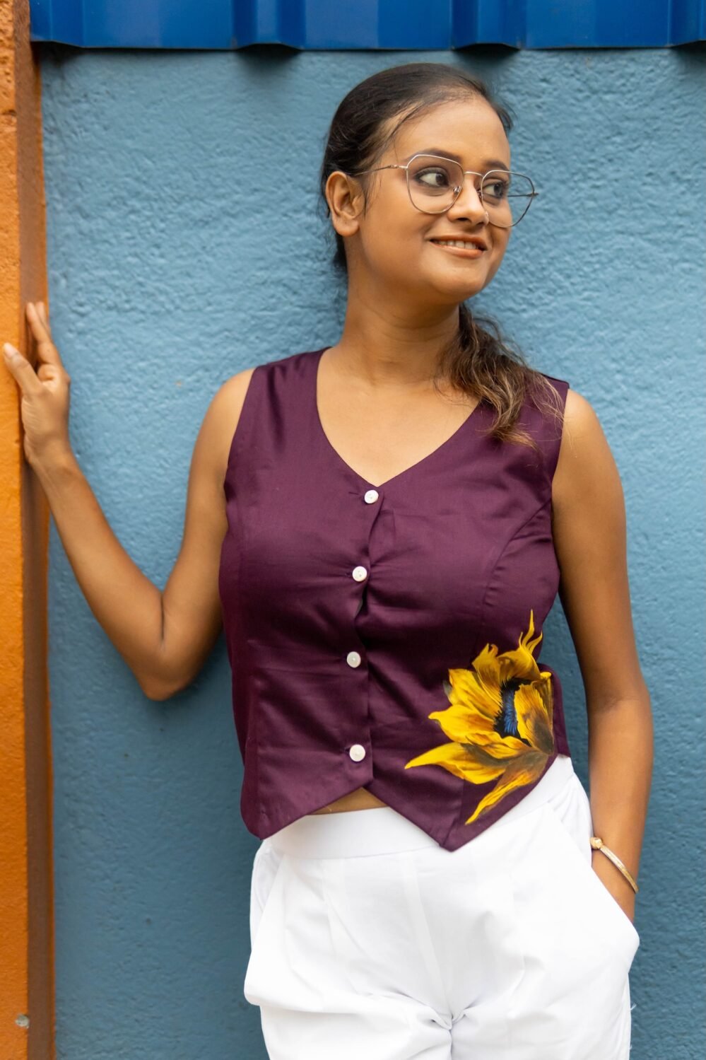 Model wearing a deep purple V-neck handpainted sunflower waist coat standing against a colorful backdrop.