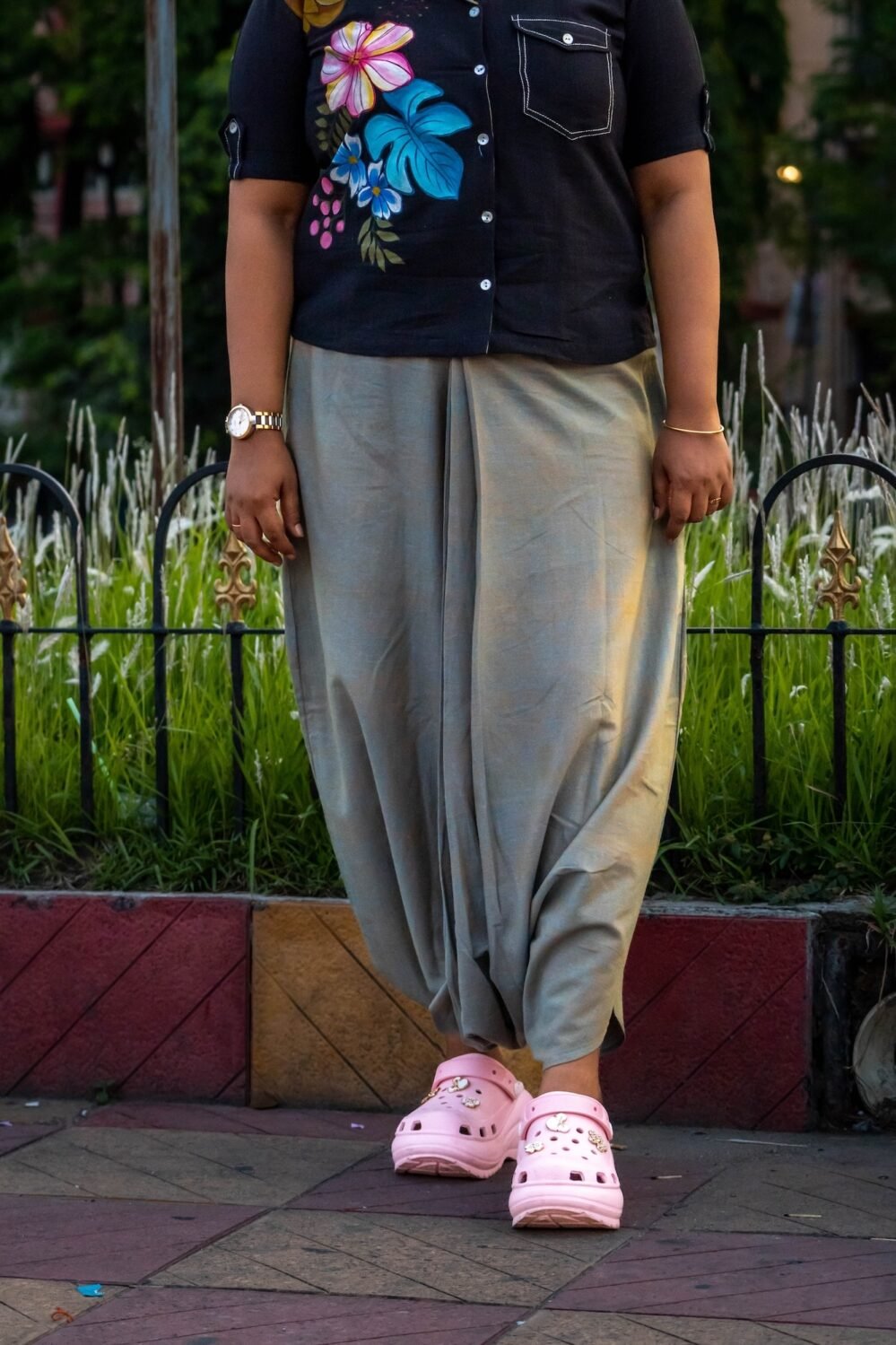 Mid-shot of sage green handloom cotton urban dhoti pants paired with a black floral hand-painted button-down top