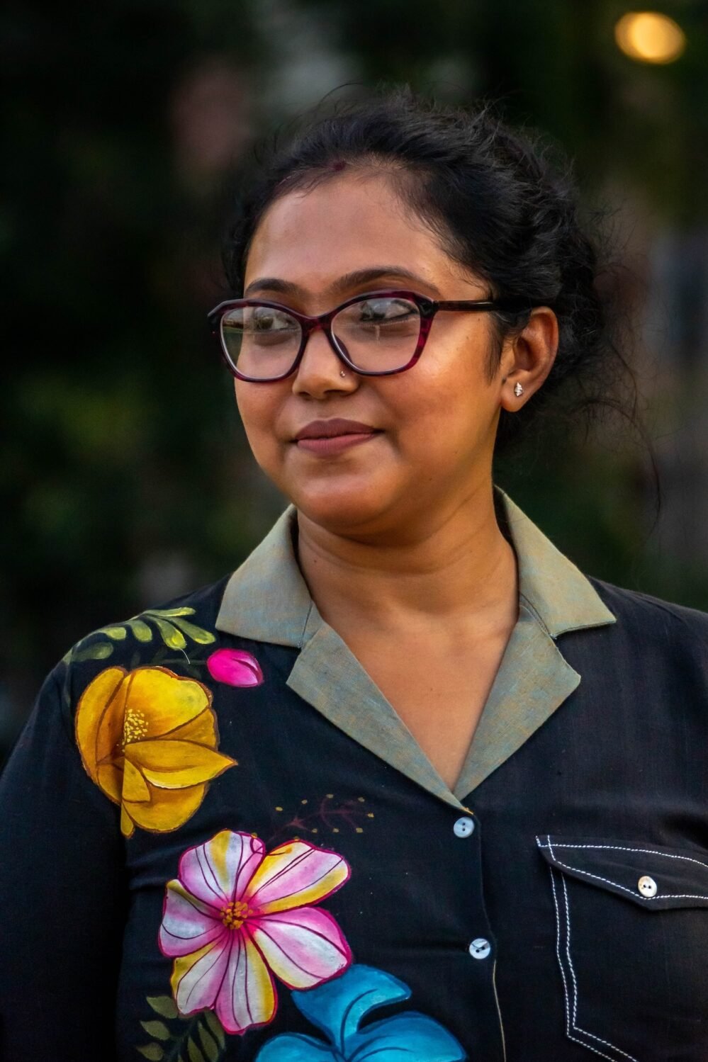 etailed shot of hand-painted yellow, pink, and blue floral artwork on a black handloom cotton top with contrast pocket stitching.
