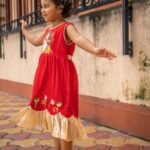 Side view of little girl dancing outdoors wearing sleeveless handpainted Durga Rani ethnic frock.