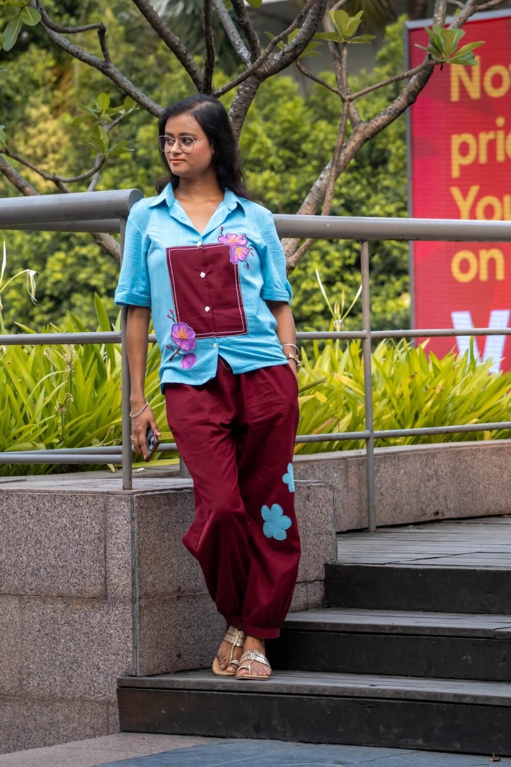 Woman wearing the Sky Blue Maroon Orchid handpainted 3D cotton shirt and pant co-ord set by Aankibukis Couture posing on outdoor steps.