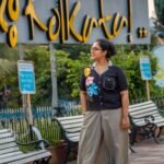 Woman wearing black handloom cotton blazer collar top with vibrant hand-painted flowers paired with sage green urban dhoti pants.