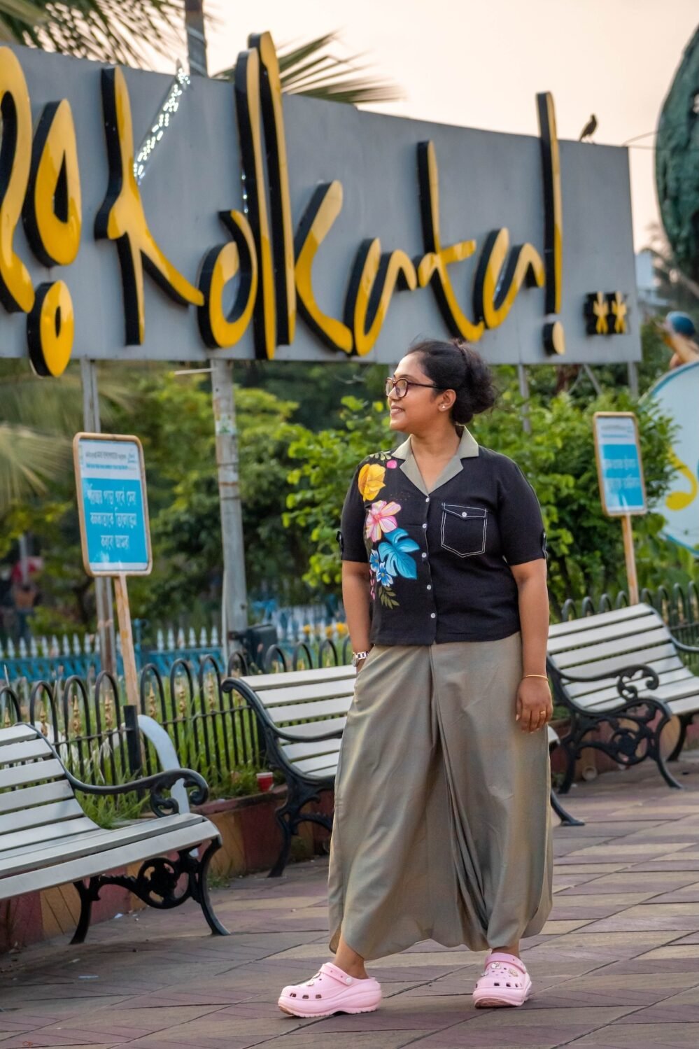 Woman wearing black handloom cotton blazer collar top with vibrant hand-painted flowers paired with sage green urban dhoti pants.