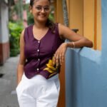 Full styling shot of a woman wearing a purple handpainted waist coat styled as a top with white trousers.