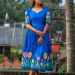 Model standing in a royal blue hand-painted tulip midi dress made from Malai cotton