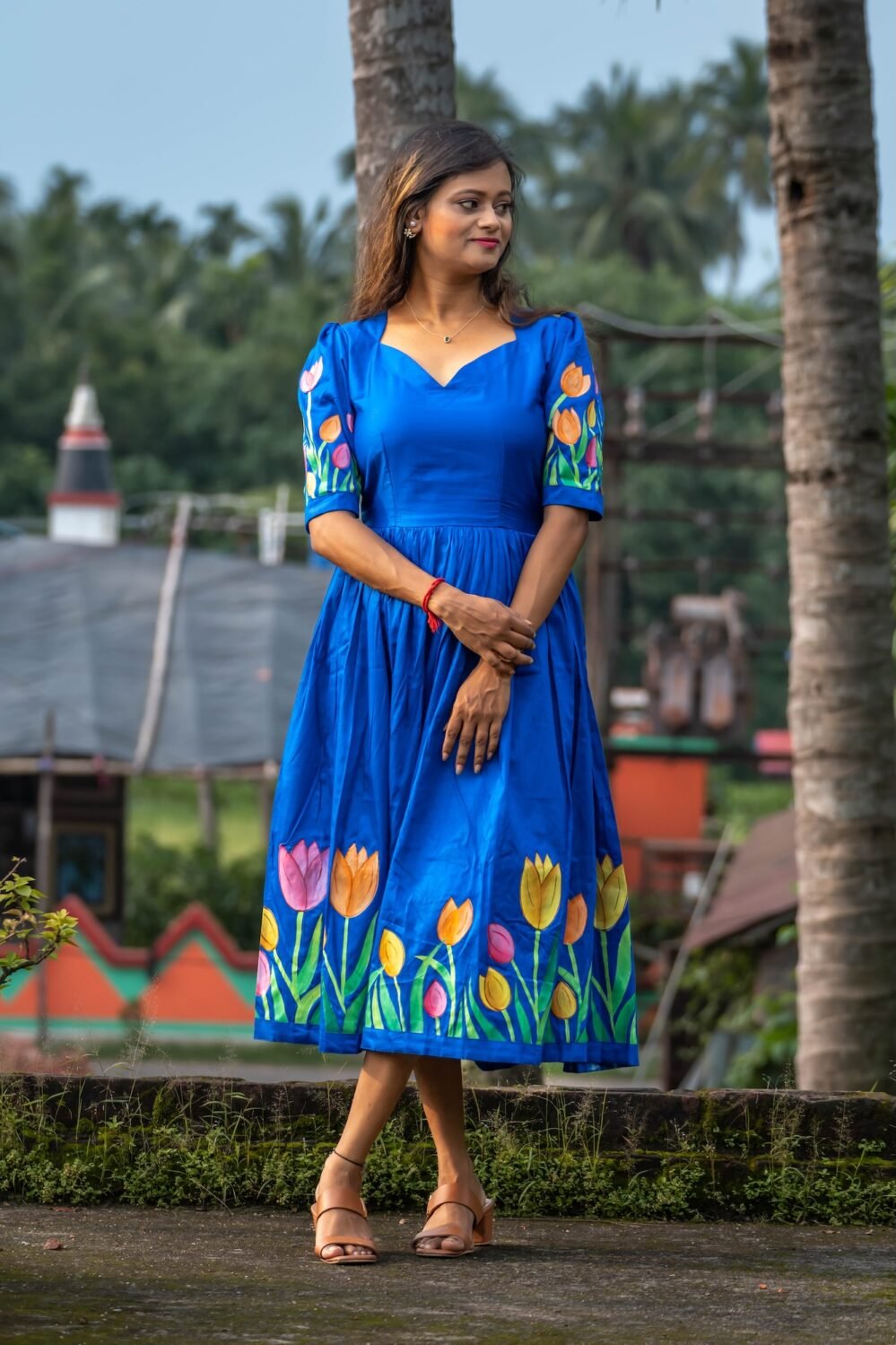 Model standing in a royal blue hand-painted tulip midi dress made from Malai cotton