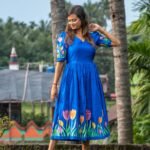 Front view of a model in a hand-painted royal blue dress with colorful tulip motifs.