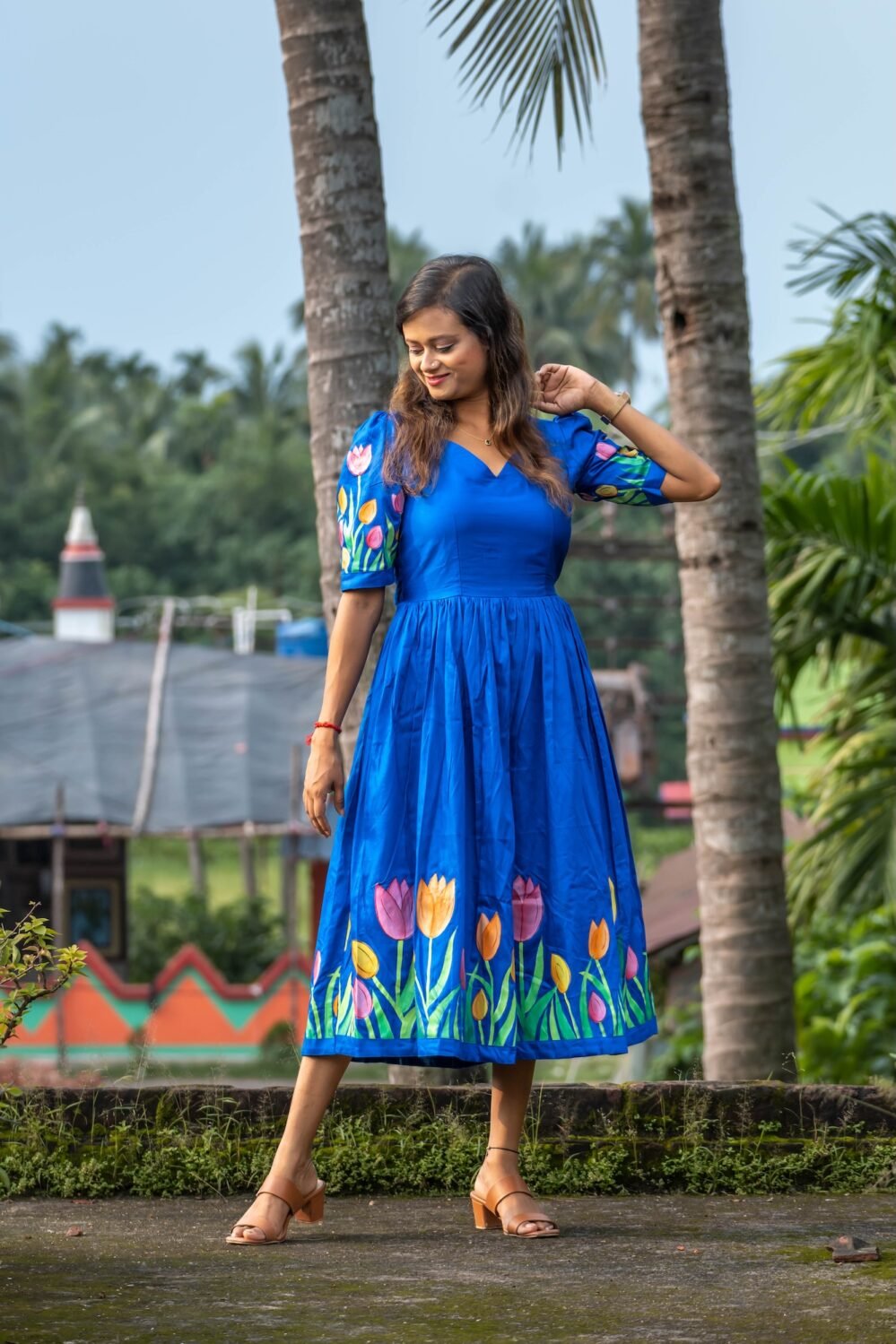 Front view of a model in a hand-painted royal blue dress with colorful tulip motifs.