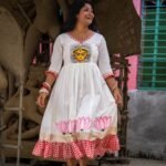 Model holding the hem of the hand-painted Annapurna dress displaying the lotus artwork.