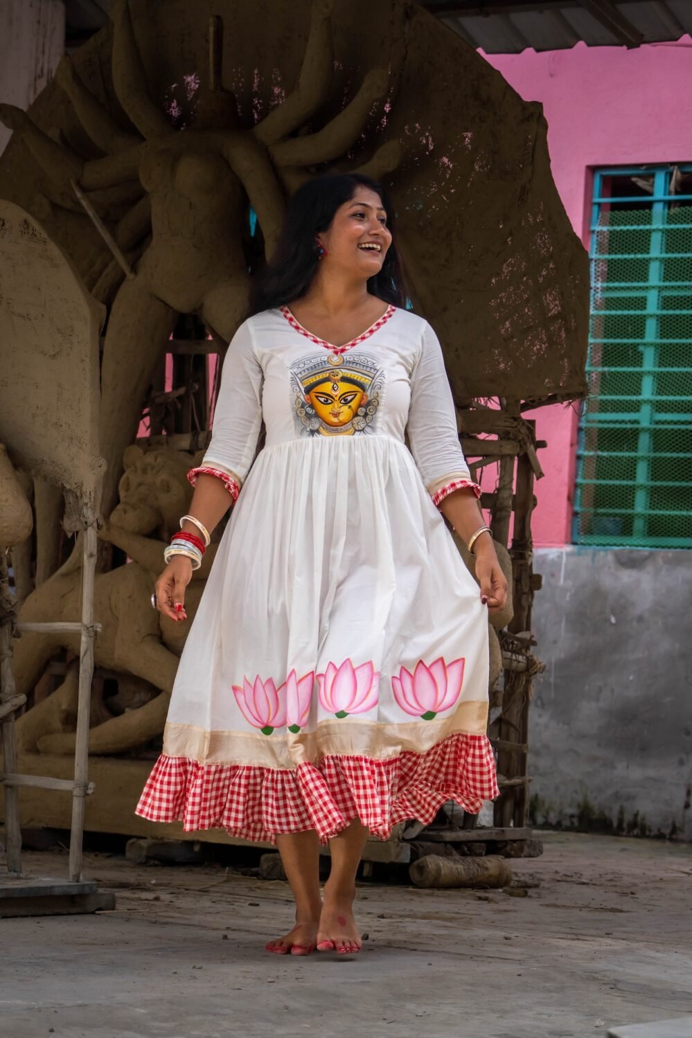 Model holding the hem of the hand-painted Annapurna dress displaying the lotus artwork.