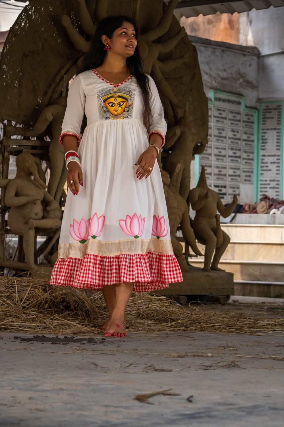 Woman standing in a clay idol workshop wearing the hand-painted Annapurna dress by Aankibukis Couture.