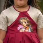 Detailed close-up shot of the handpainted Maa Durga lotus artwork on the bodice of the maroon Chhoto Uma pure cotton frock.