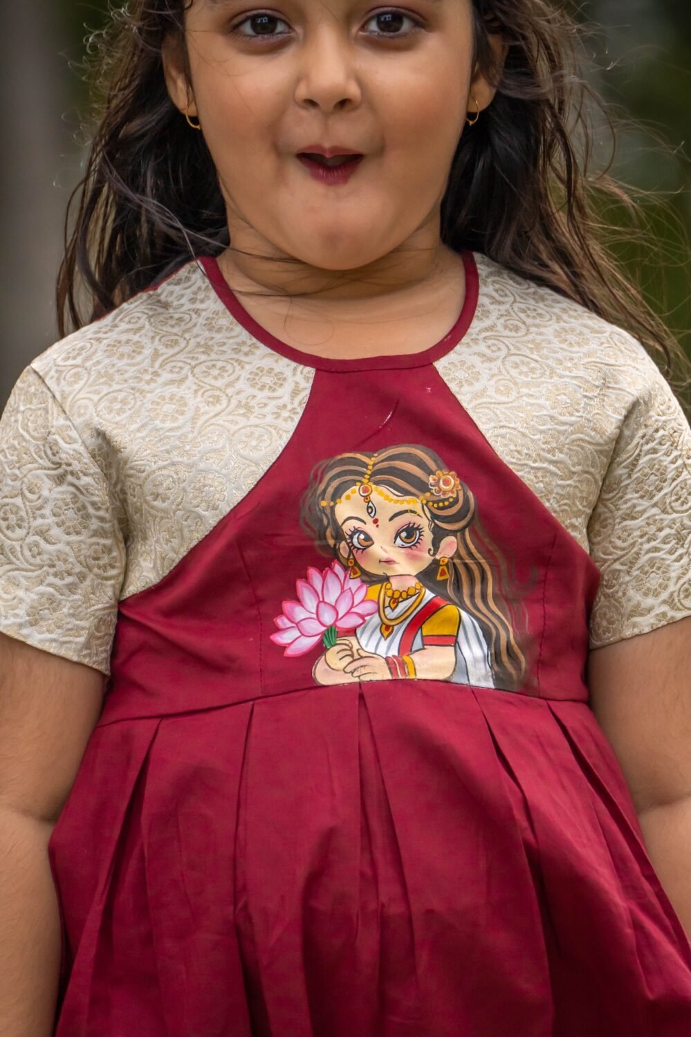 Detailed close-up shot of the handpainted Maa Durga lotus artwork on the bodice of the maroon Chhoto Uma pure cotton frock.