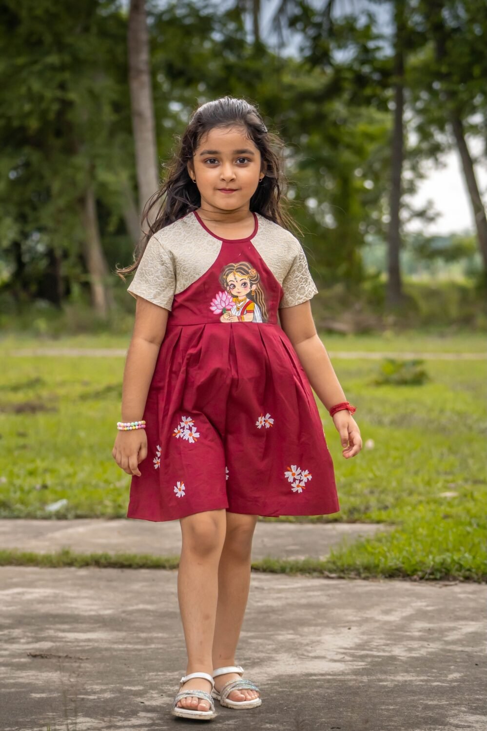 Front full shot of a girl modeling the maroon and cream Chhoto Uma handpainted frock with small white flower details.