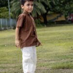 Boy standing on grass wearing Kisholoy hand-painted brown mandarin collar cotton shirt