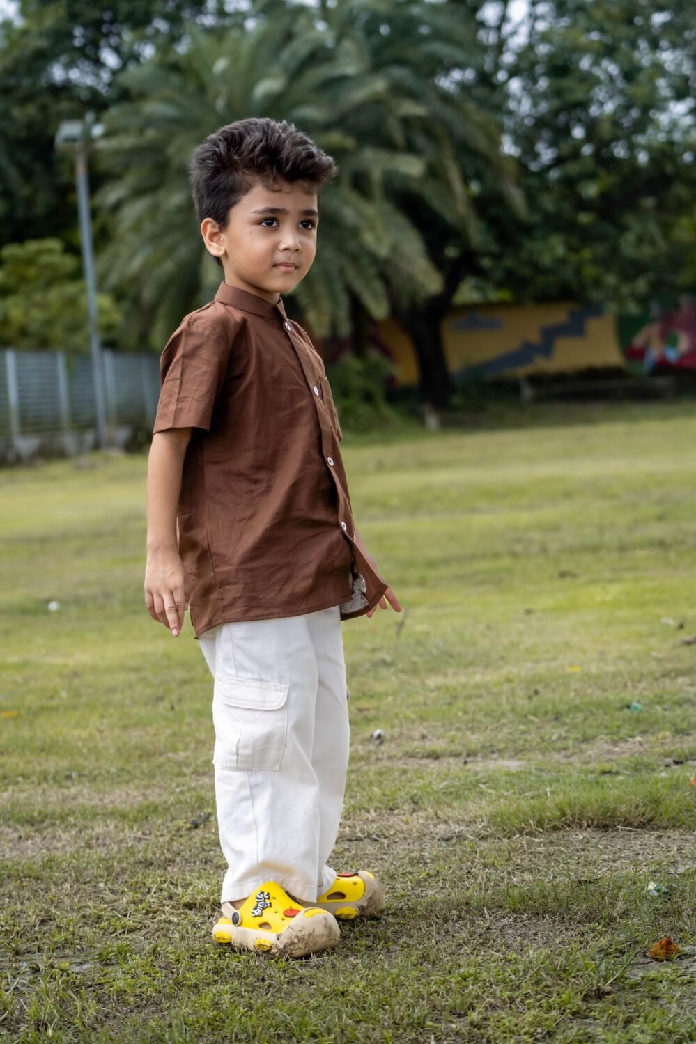 Boy standing on grass wearing Kisholoy hand-painted brown mandarin collar cotton shirt