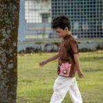Boy walking in park wearing Kisholoy chocolate brown shirt with white cargo trousers