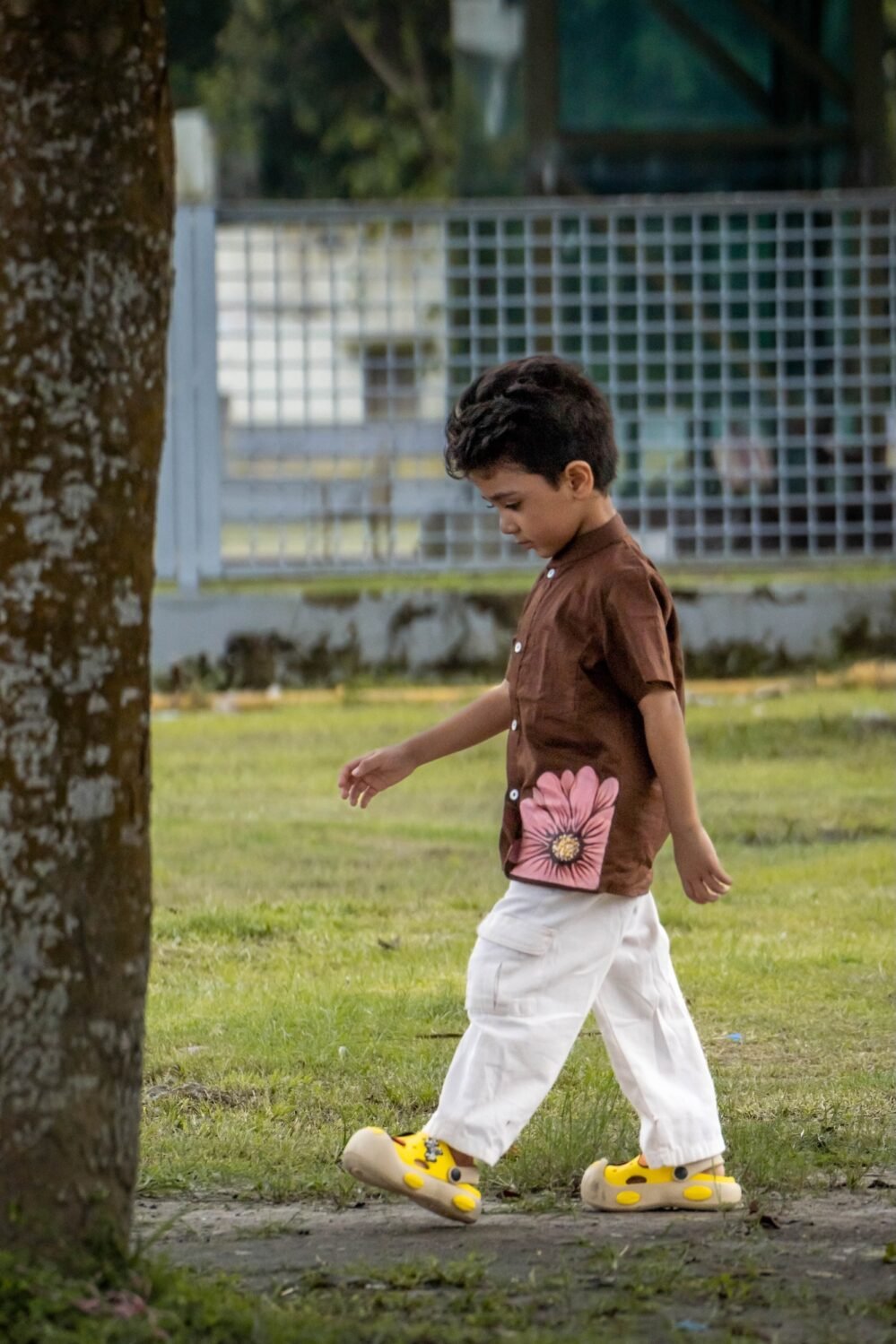 Boy walking in park wearing Kisholoy chocolate brown shirt with white cargo trousers