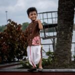 Boy wearing Kisholoy chocolate brown mandarin collar shirt with white festive dhoti