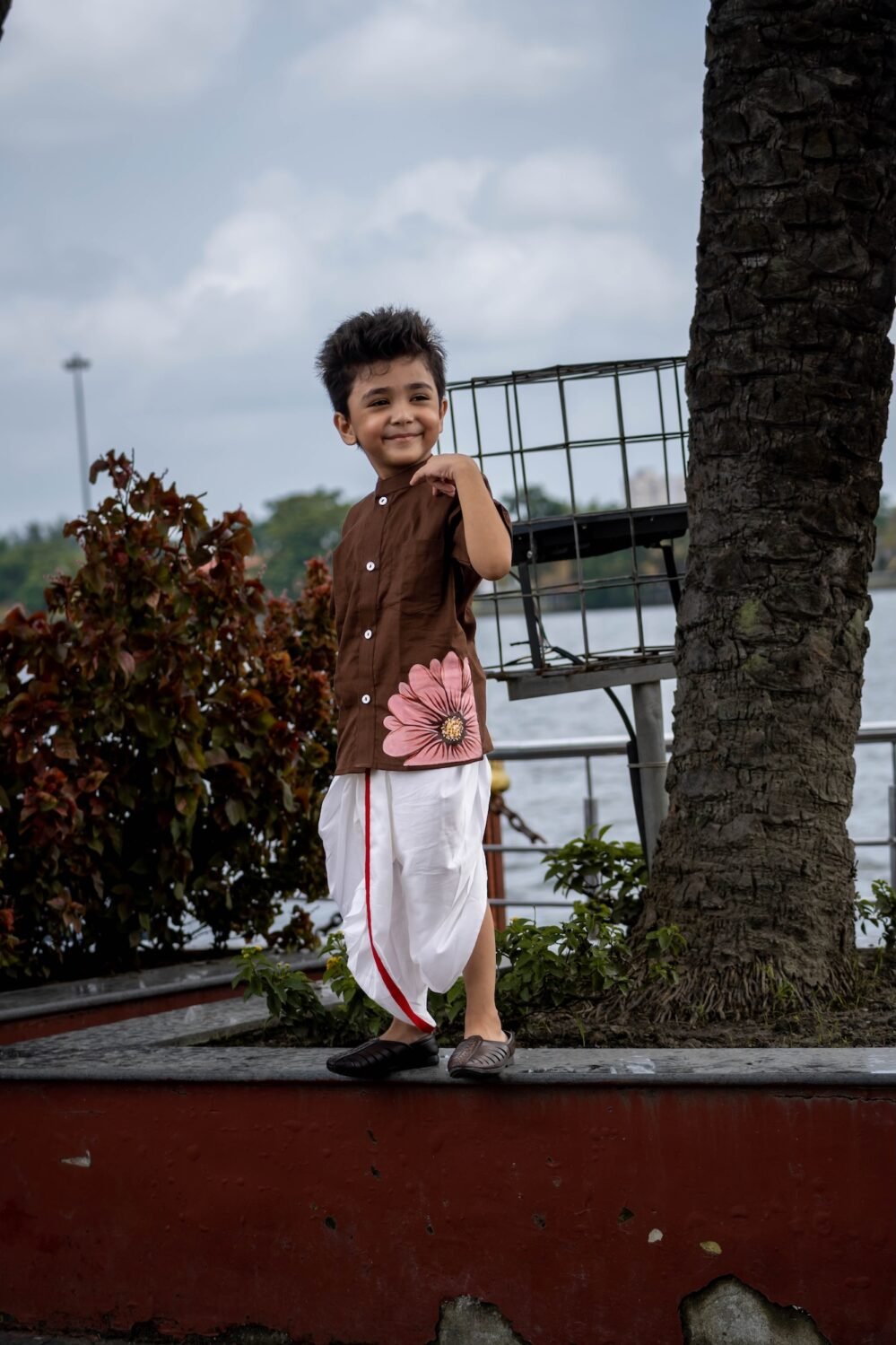 Boy wearing Kisholoy chocolate brown mandarin collar shirt with white festive dhoti