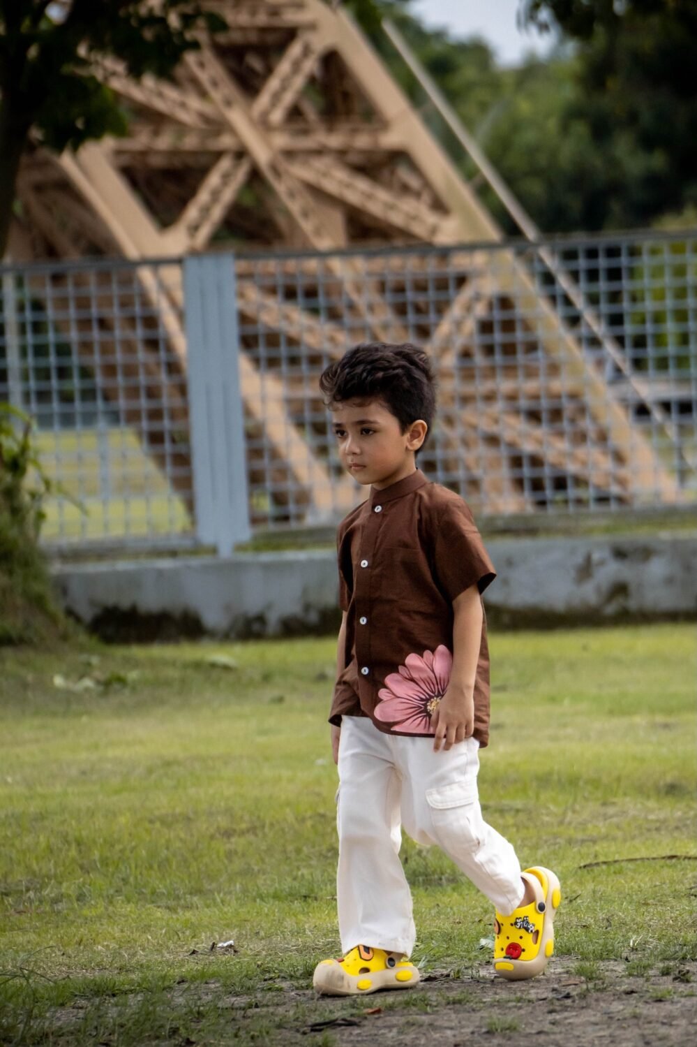 Boy walking outdoors wearing Kisholoy chocolate brown hand-painted floral shirt
