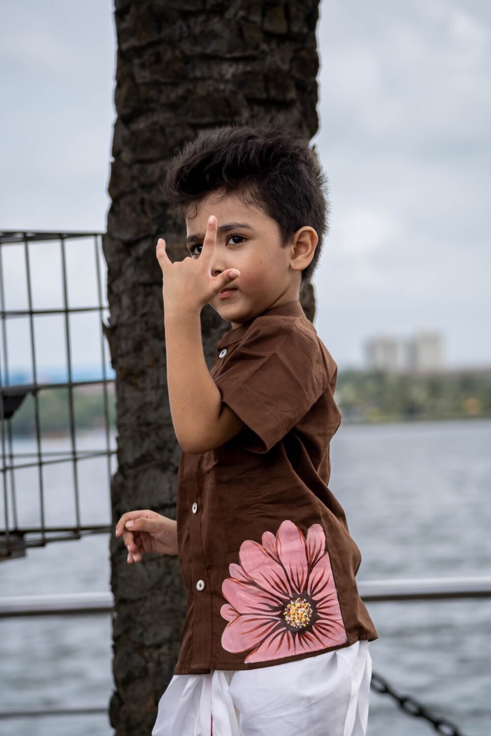 Close-up of boy in Kisholoy chocolate brown hand-painted cotton shirt showing pink floral artwork