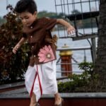 Young boy running happily outdoors in Kisholoy chocolate brown hand-painted shirt