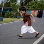 Boy running outdoors wearing Kisholoy chocolate brown hand-painted shirt and white dhoti