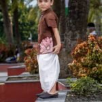 Side profile of young boy wearing hand-painted floral chocolate brown cotton shirt