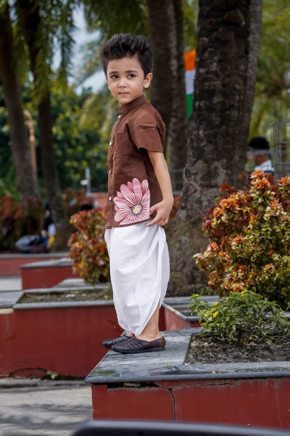 Side profile of young boy wearing hand-painted floral chocolate brown cotton shirt